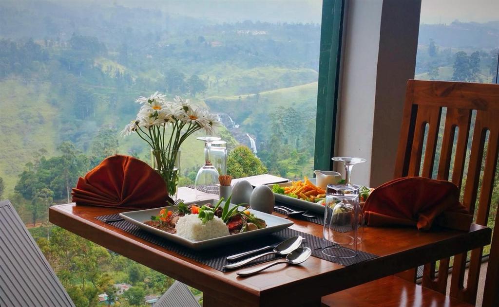 una mesa con un plato de comida con vistas en Waterfalls View Resort, en Talawakele
