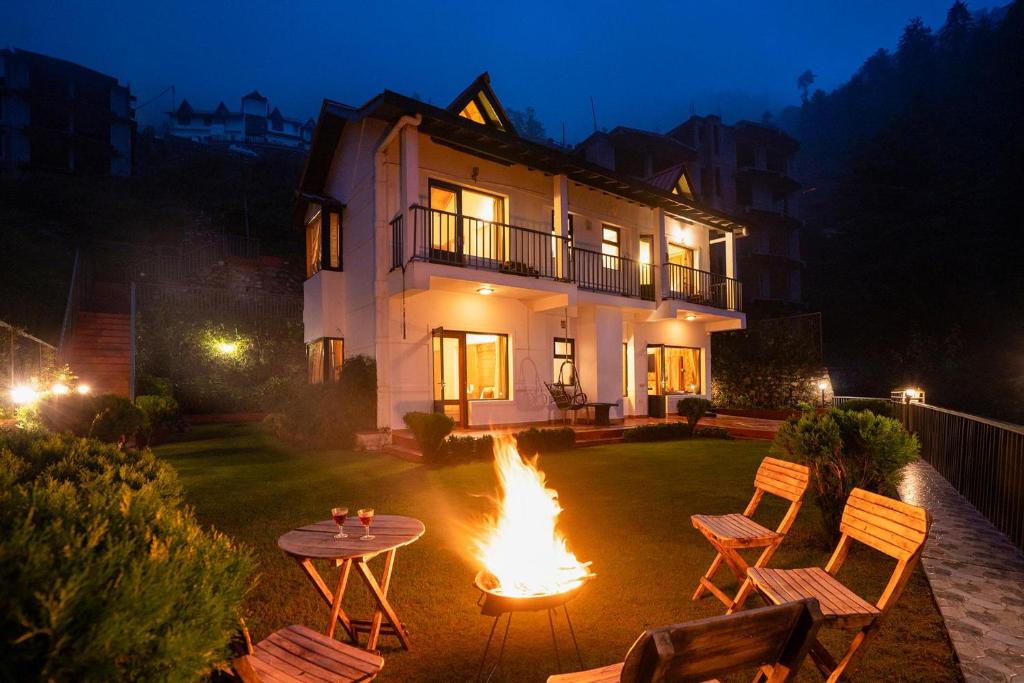 un foyer extérieur en face d'une maison la nuit dans l'établissement StayVista at Under The Pines, à Shimla