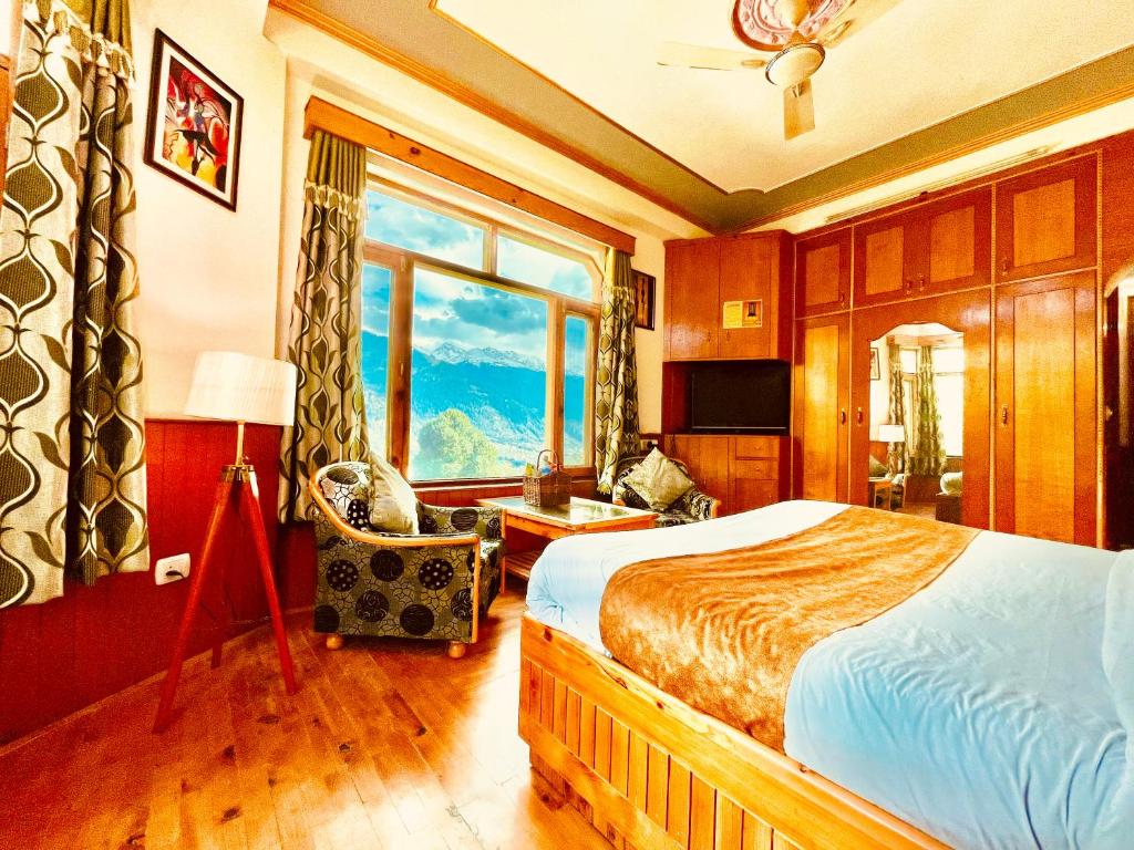 a bedroom with a bed and a large window at Shree Ram Cottage, Manali ! 1,2,3 Bedroom Luxury Cottages Available in Manāli