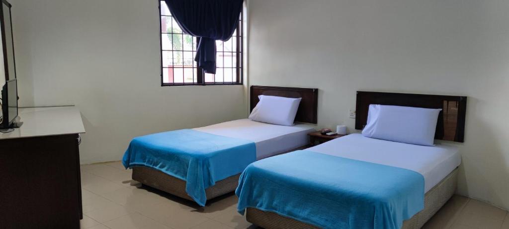 een kamer met 2 bedden met blauwe en witte lakens bij Gold Hill Hotel in Jerantut