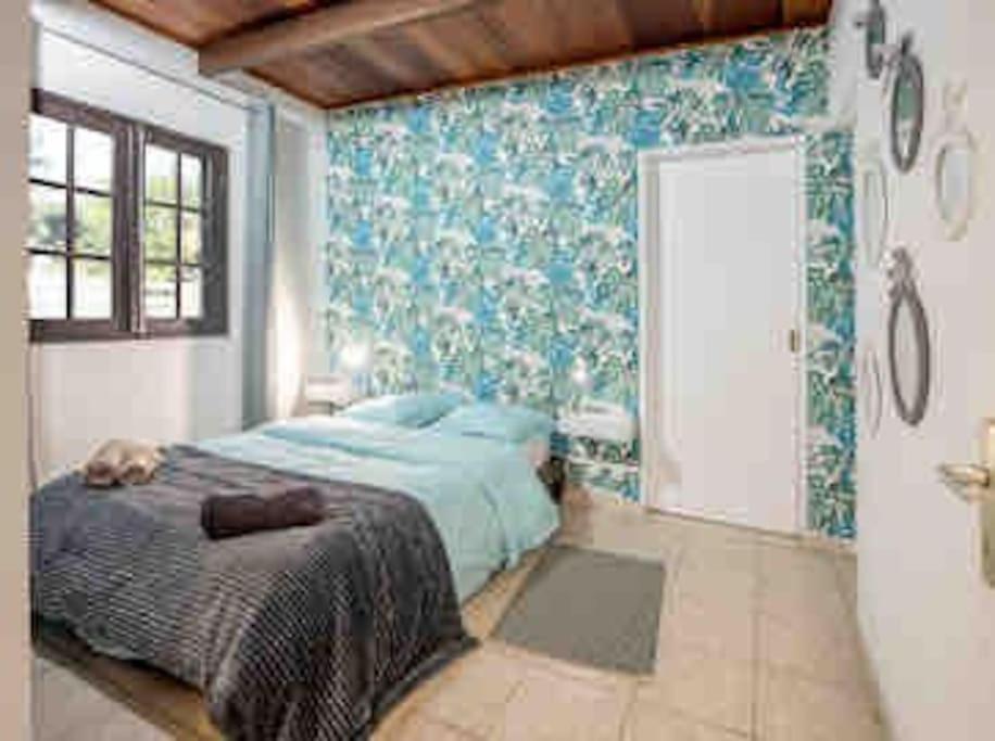 a bedroom with a bed and a door with blue wallpaper at Le Chakouat in Cilaos