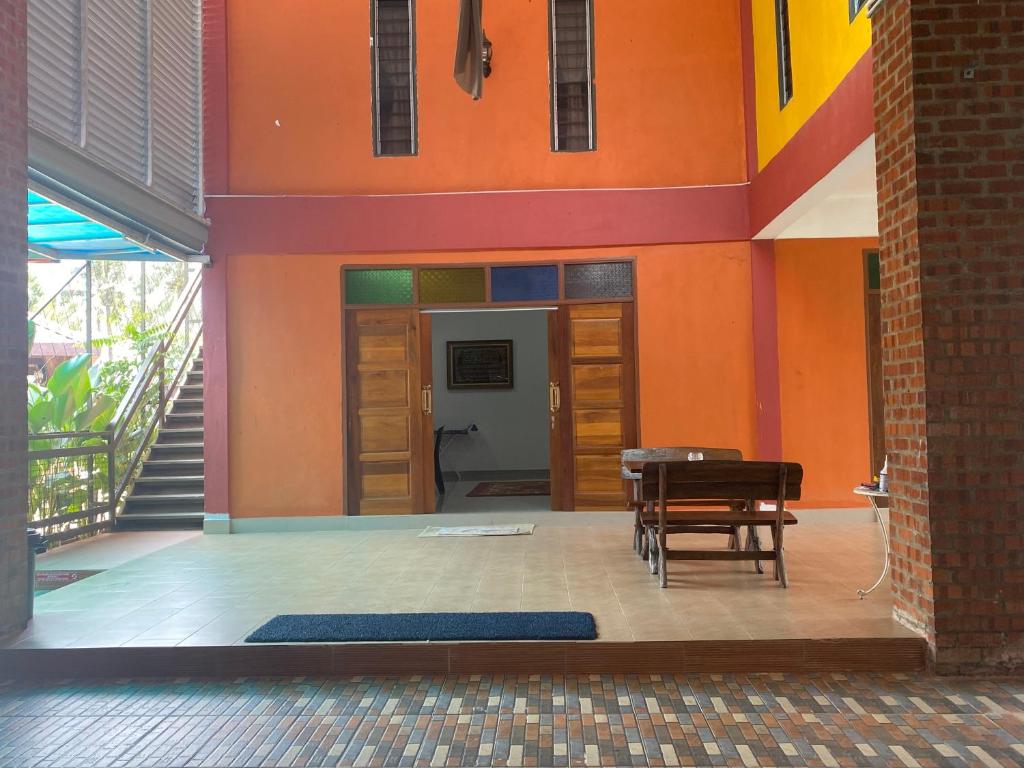 Laman Norras Homestay في Kepala Batas: غرفة بحائط برتقالي مع طاولة وكراسي