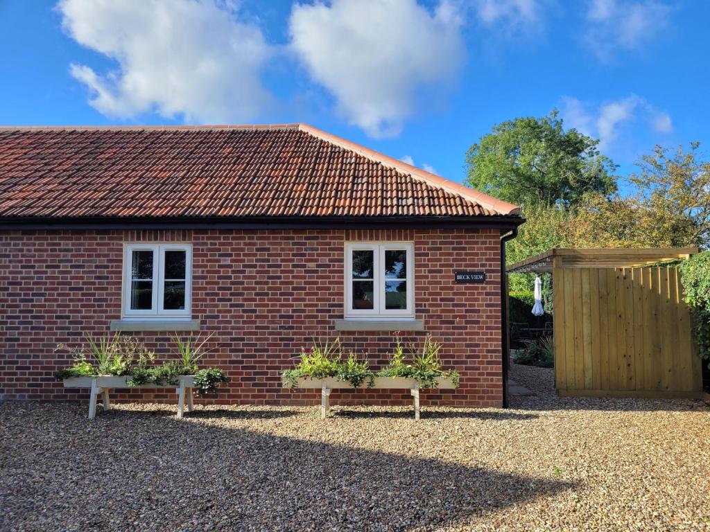 a red brick house with two windows and plants at Beck View in Norwich