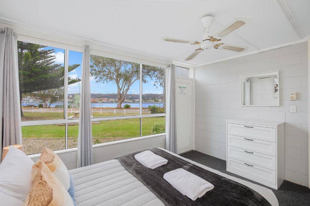a bedroom with a bed and a large window at Fishpen Holiday Apartments in Merimbula