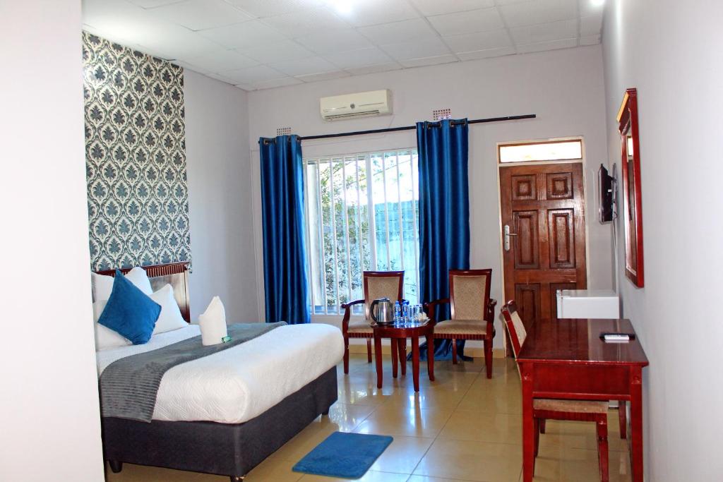 Habitación de hotel con cama, mesa y ventana en Fatmols Hotels, en Lusaka