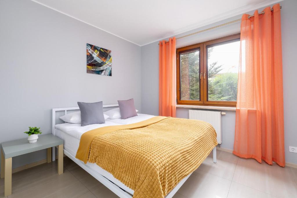 um quarto com uma cama e uma janela com cortinas laranja em Mondrian Cracow - 2 Bedroom Apartment for Home Office by Renters em Cracóvia