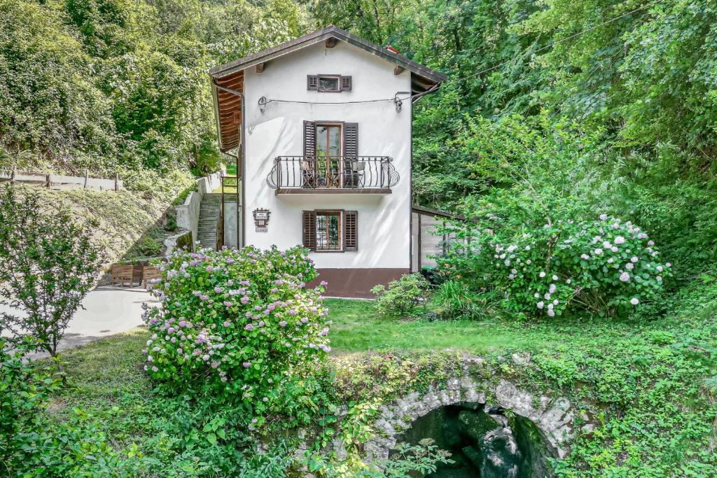 House By The Stream في Avče: منزل أبيض صغير مع شرفة في حديقة