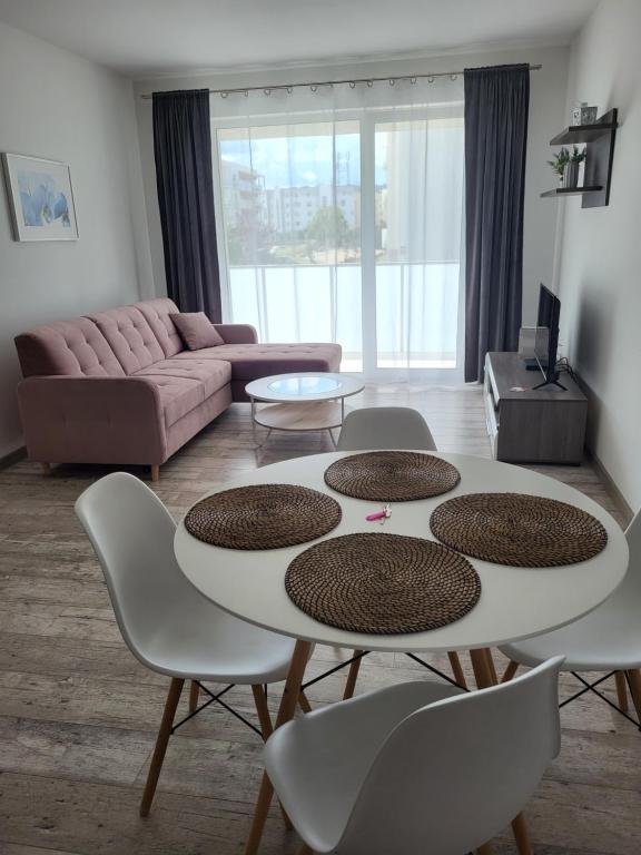 ein Wohnzimmer mit einem Tisch, Stühlen und einem Sofa in der Unterkunft Caskada Modern Apartments 2 in Słupsk