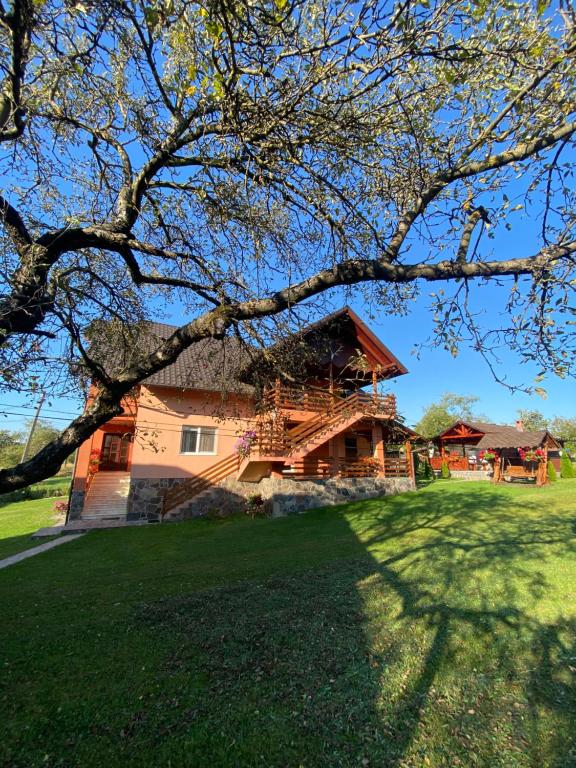 uma casa grande com um deque num campo de relva em Pensiunea Martuca em Şurdeşti