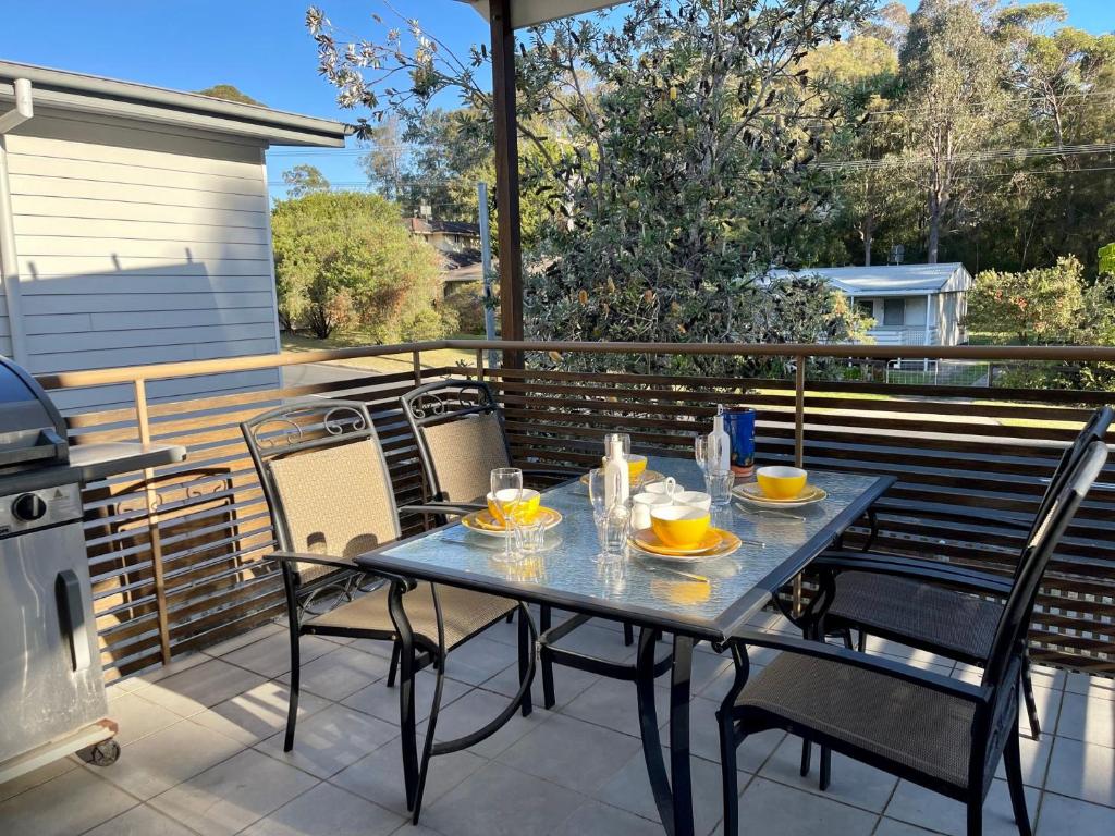 a table and chairs on a balcony with a grill at Beach Retreat in Mollymook