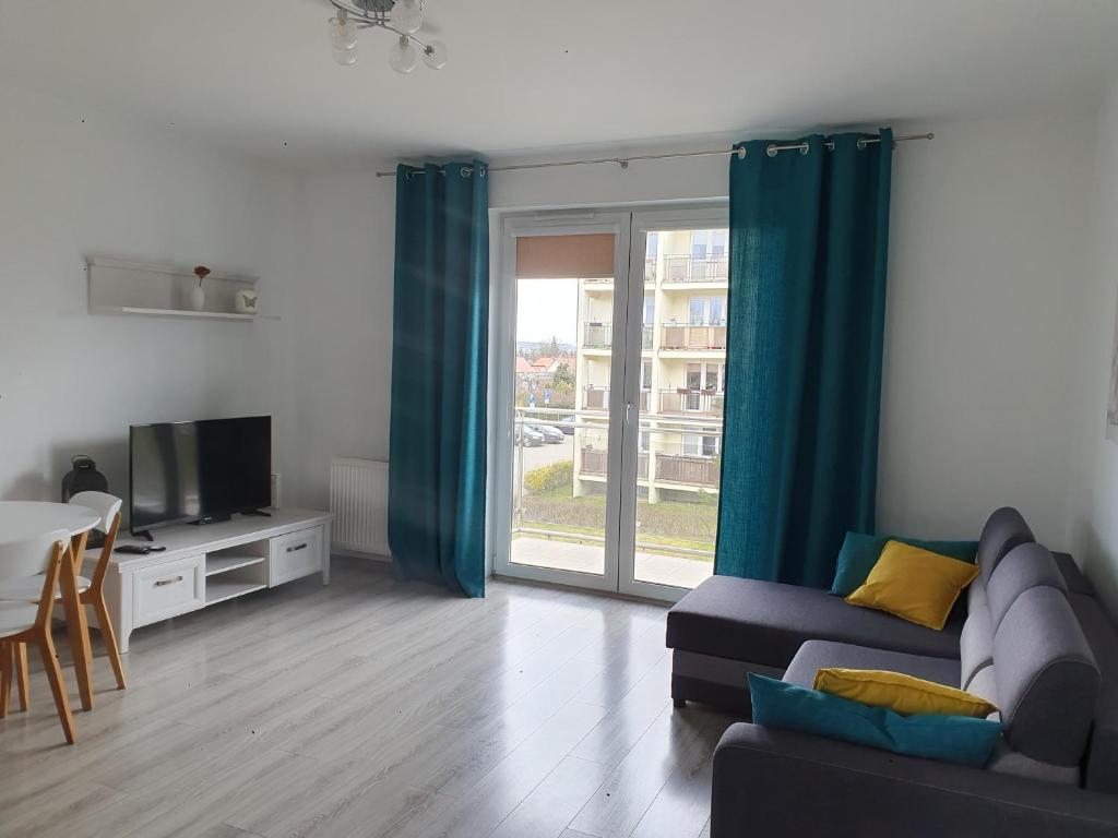 a living room with a couch and a television at Narutowicza Modern Apartment 2 in Słupsk