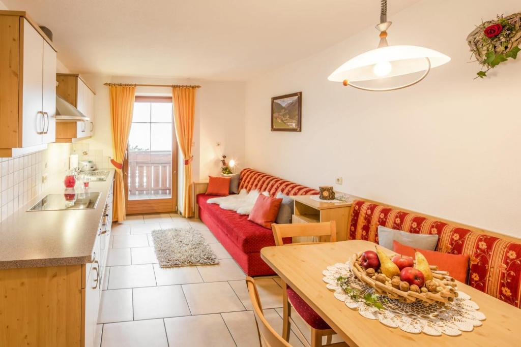 Una cocina y una sala de estar con un sofá rojo. en Voppichlhof App Alpenrose, en San Giacomo