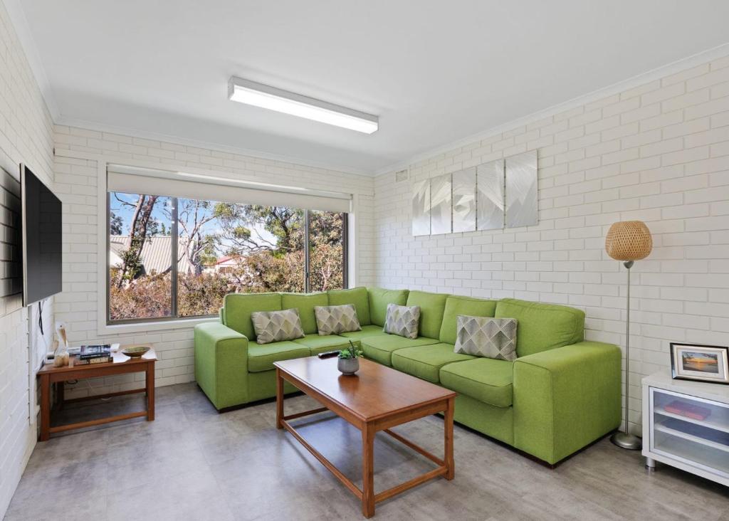 a living room with a green couch and a table at Serene Nature Retreat in Rhyll