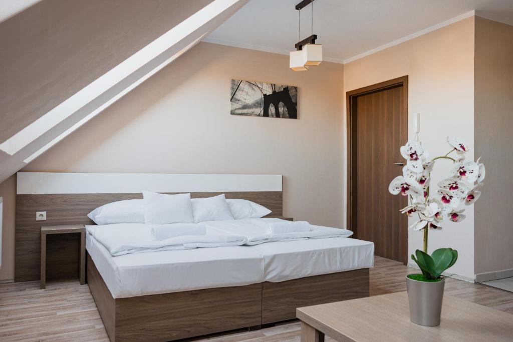 ein Schlafzimmer mit einem großen weißen Bett und einem Tisch in der Unterkunft Zafír Apartmanház in Sárvár