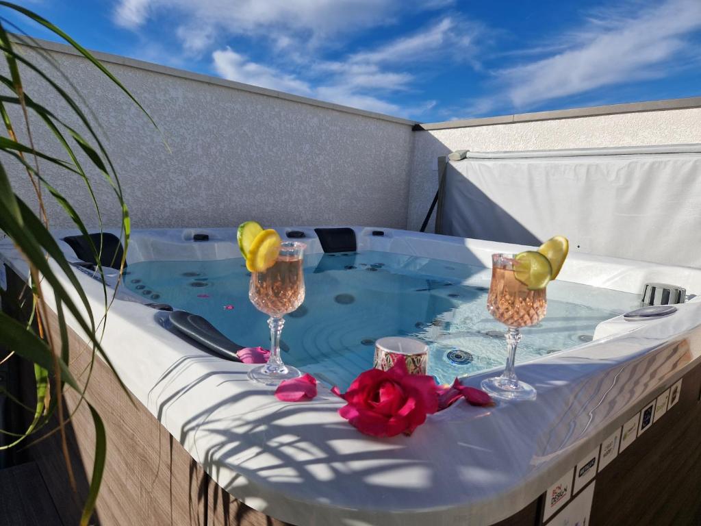 a hot tub with two wine glasses and roses at Maison récente 4* proche plage avec SPA privatif in Longeville-sur-Mer