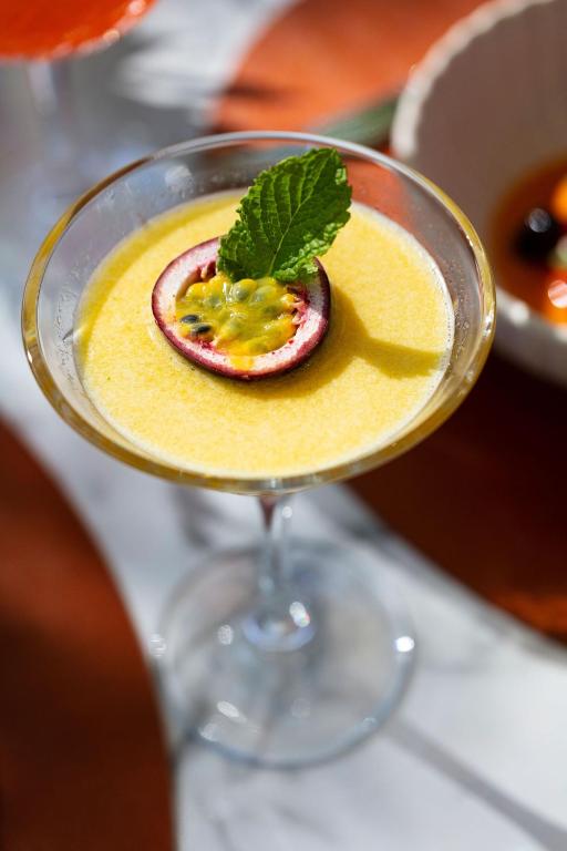 a cocktail with a fruit garnishment in a glass at La Bastide Bourrelly - Mathias Dandine in Cabriès