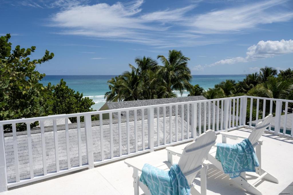 a balcony with two chairs and the beach at Lillian's Cottage cottage in Harbour Island