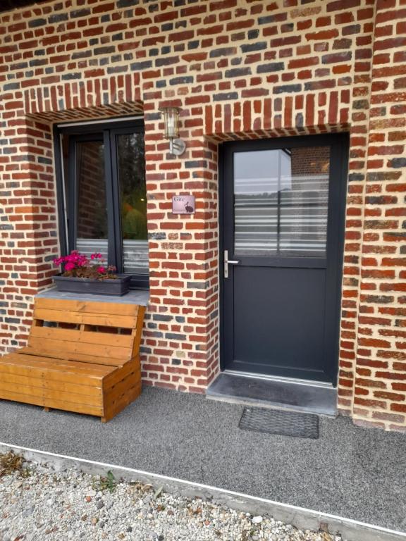 a brick building with a black door and two windows at Chambre d hotes le pigeonnier in Fromelles