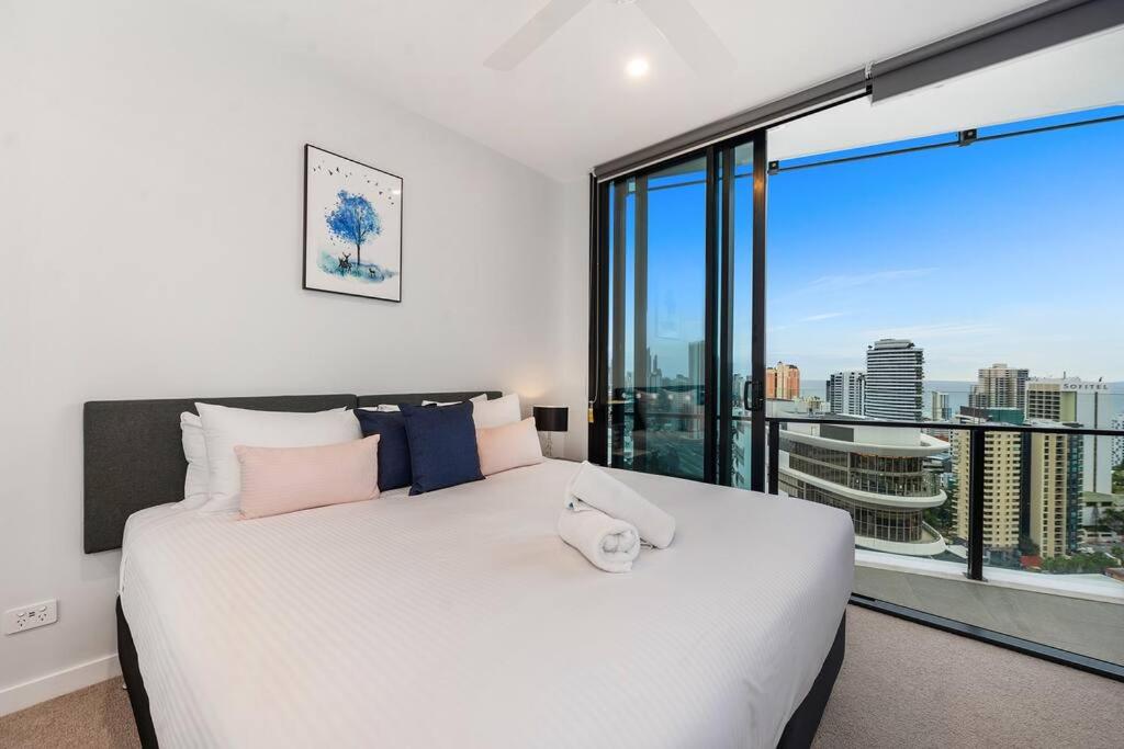 1 dormitorio con 1 cama blanca grande y ventana grande en Above Broadbeach casino 1BRplus Study ocean-city views, en Gold Coast