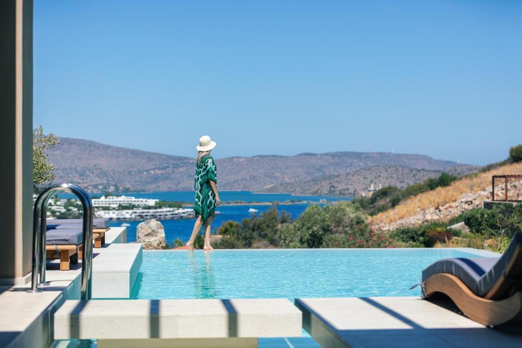 a person standing on the edge of a swimming pool at Villa Katy in Agios Nikolaos