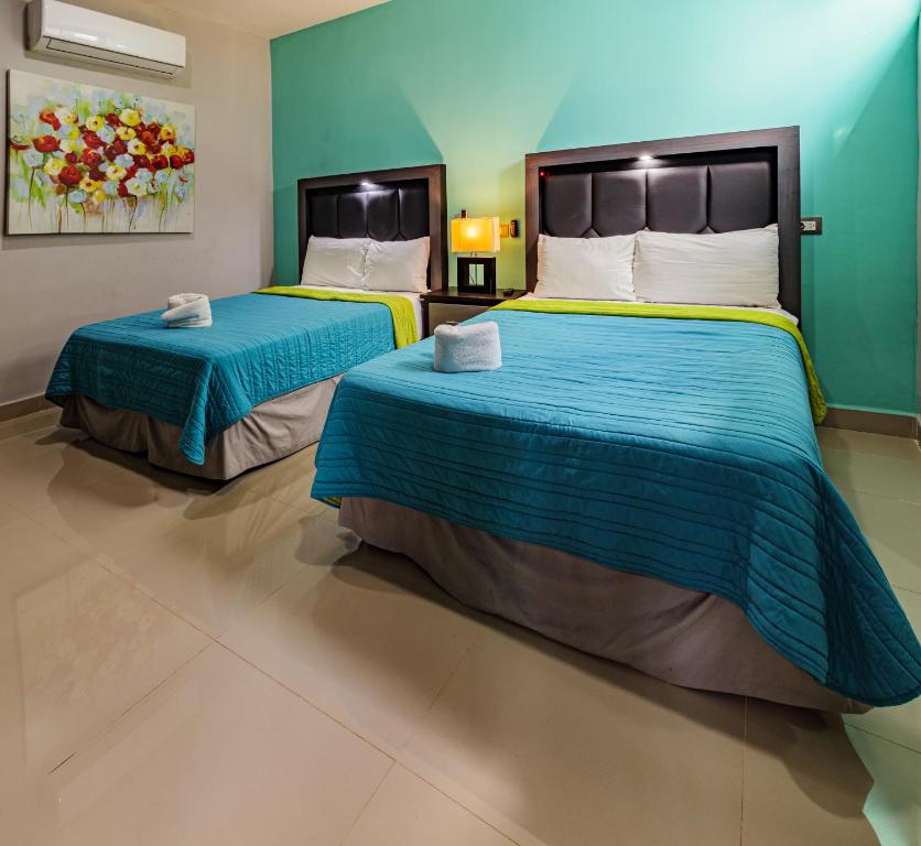 2 camas en una habitación de hotel con paredes azules en Hotel Suites Paraíso, en Mérida