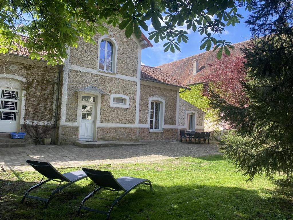zwei Stühle im Gras vor einem Haus in der Unterkunft LES DOUVES, charmante dépendance du château in Crèvecoeur-en Brie