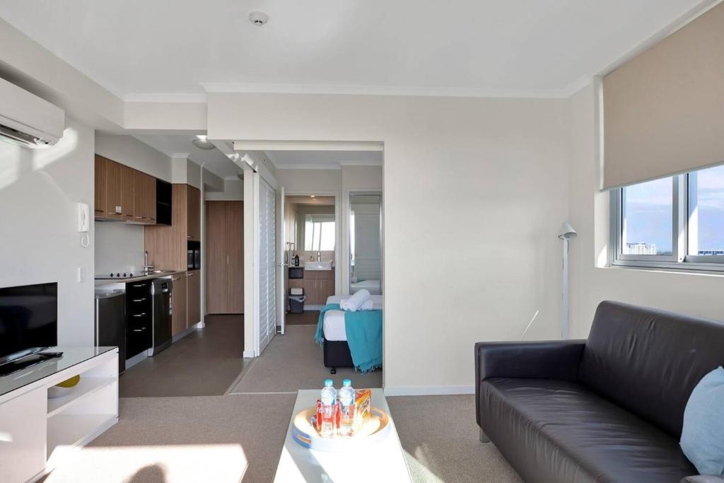 un soggiorno con divano nero e una cucina di Modern Dual Key Apt w Pool in the heart of Mackay a Mackay