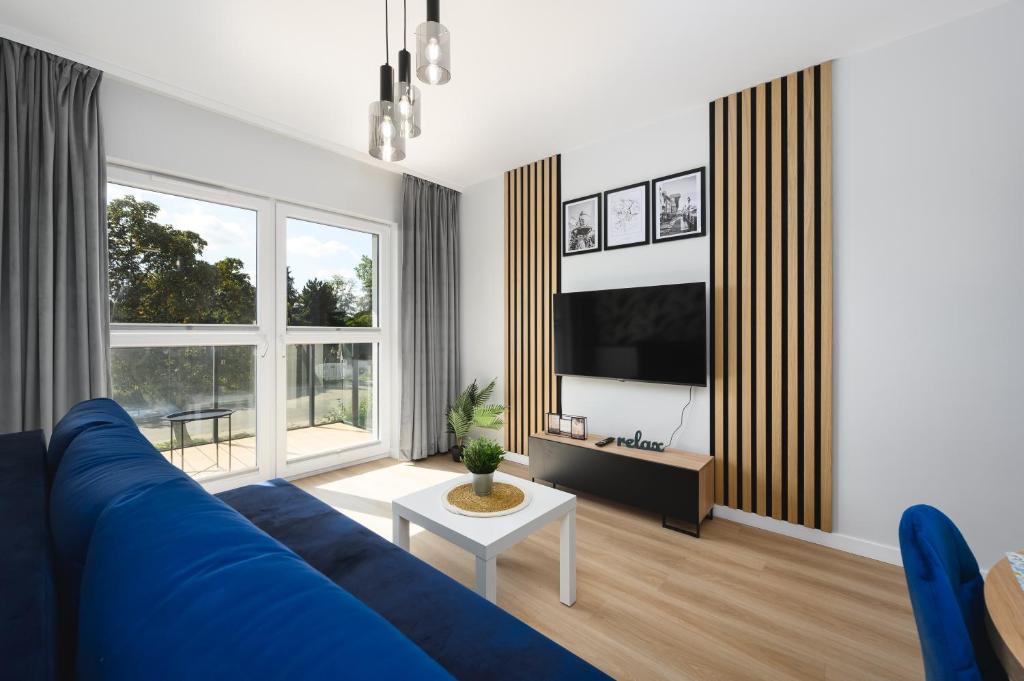 a living room with a blue couch and a tv at Apartament Baltic Breeze ProstyWynajem Gdańsk Brzeźno in Gdańsk