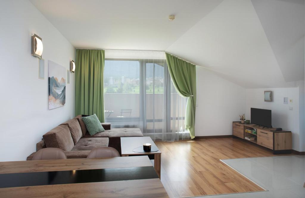 a living room with a couch and a large window at Pirin Bliss Apartment Ski, Spa and Relax at Terra Complex in Razlog