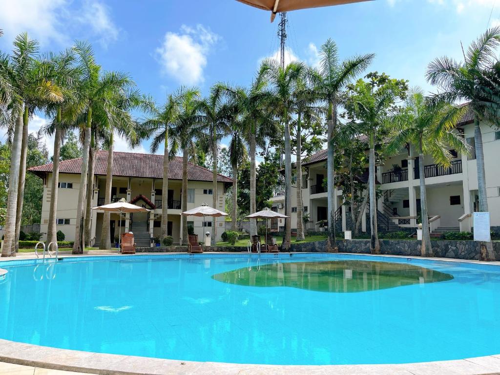 una gran piscina frente a un edificio con palmeras en Khách Sạn Hoàng Mai Dung Quất, en Bình Sơn