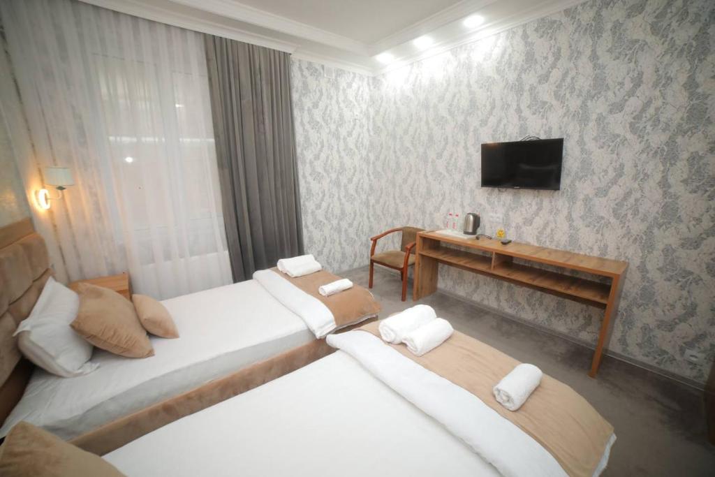 Habitación de hotel con 2 camas y TV en Hotel Tinchlik Plaza, en Urganch