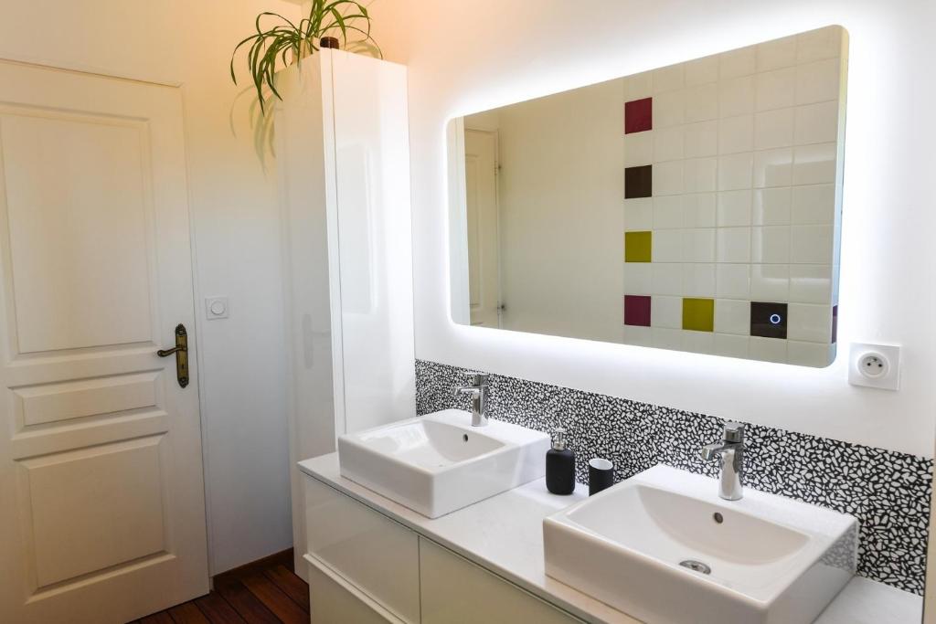 a bathroom with two sinks and a mirror at Maison Mélèry in Saint-Pierre-du-Val