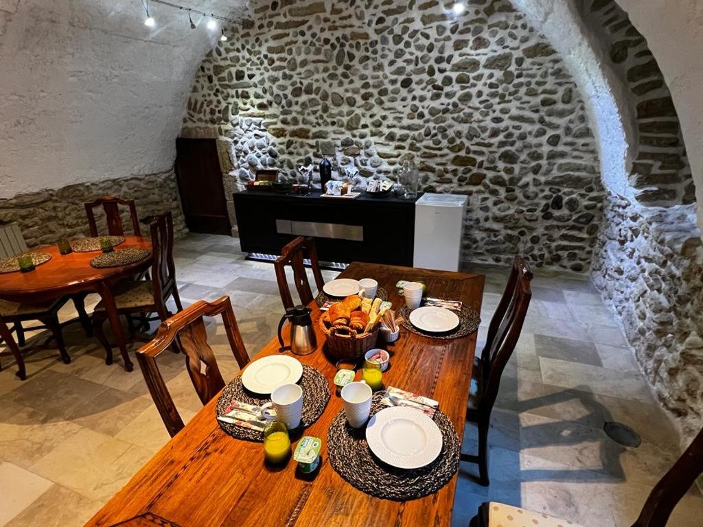 a dining room with a table and chairs and a stone wall at Les Remparts in Mirepoix