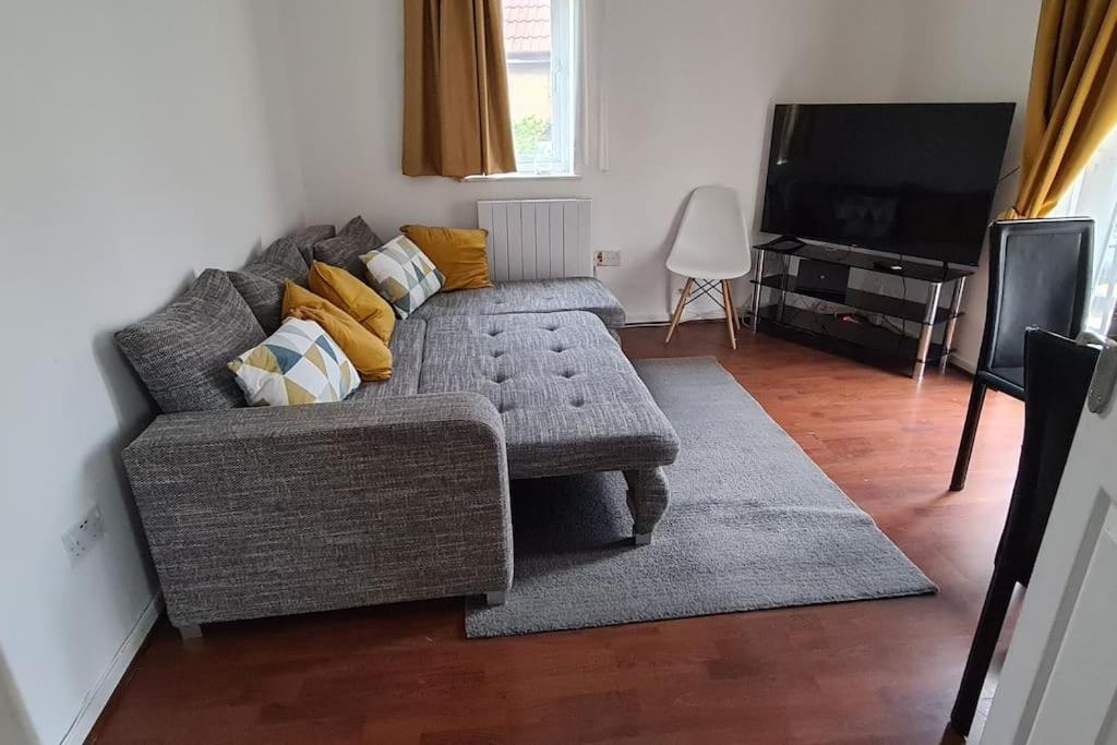 a living room with a gray couch and a television at Private 2 Bed Flat close to EXCEL & CITY AIRPORT in London