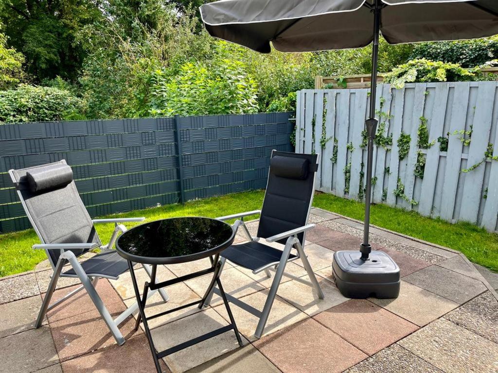 two chairs and a table and an umbrella on a patio at An der Allee 7 App in Dahme