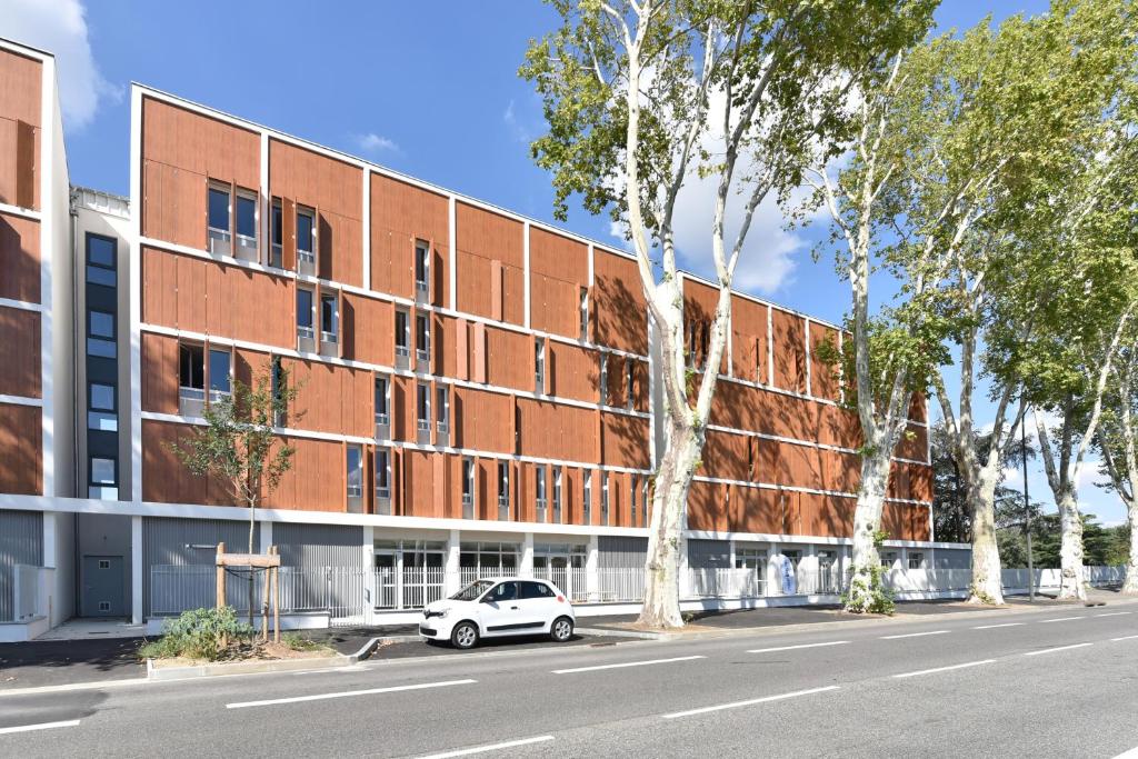 um carro branco estacionado em frente a um edifício de tijolos em Student Factory Toulouse Zénith em Toulouse