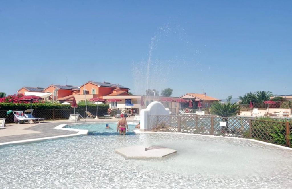 un enfant debout dans une piscine avec une fontaine dans l'établissement ISA-Residence with swimming pool in Mazzanta at only 600 meters from the beach, apartments with air conditioning and private outdoor area, à Mazzanta
