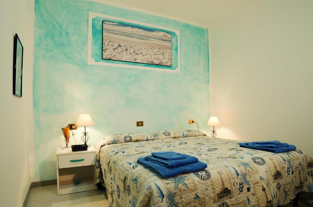 - une chambre avec un lit et des serviettes bleues dans l'établissement Il Melograno, à Arzachena