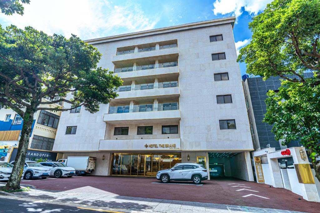 un edificio con coches estacionados frente a él en Hotel The Grang Seogwipo en Seogwipo