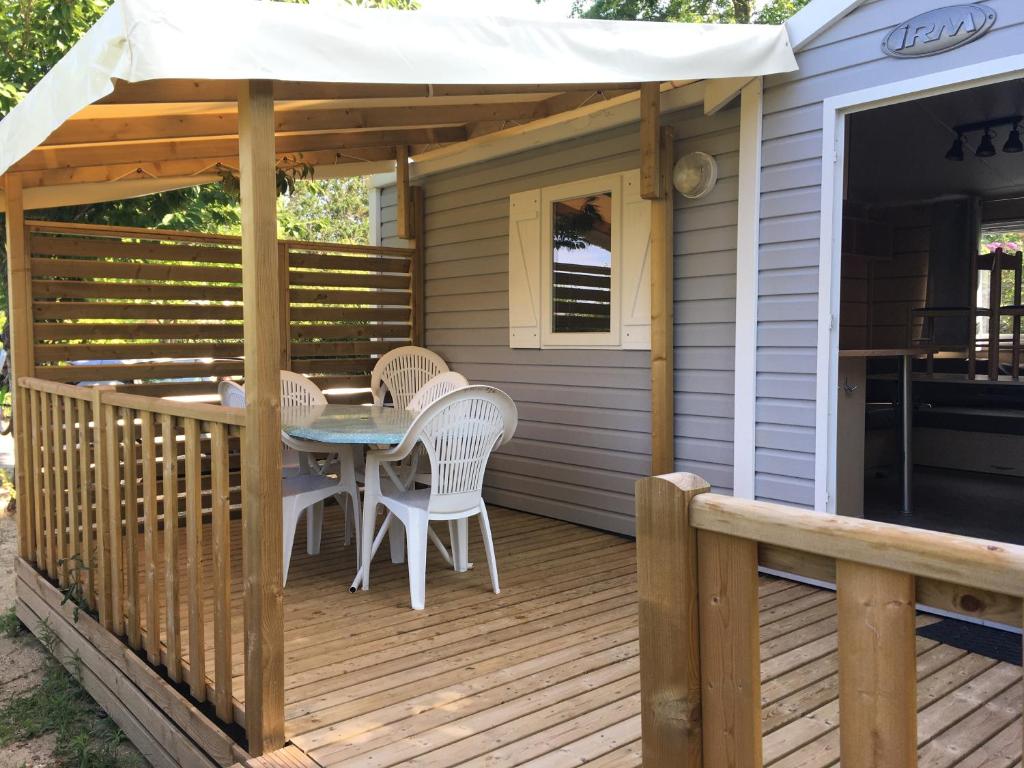 una terraza con mesa, sillas y sombrilla en Mobile home climatisé en Touraine, calme et ombragé en Trogues
