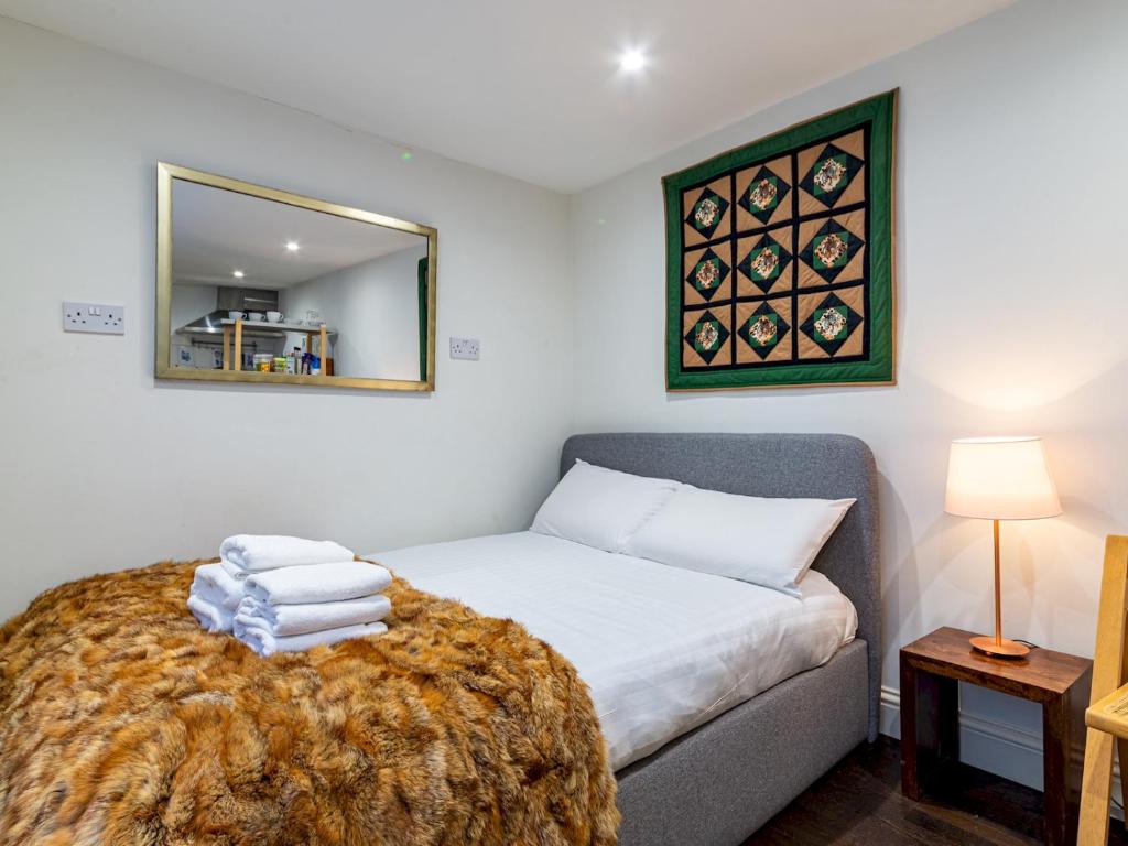 - une petite chambre avec un lit et un miroir dans l'établissement Pass the Keys Cozy studio flat in trendy Brixton, à Londres