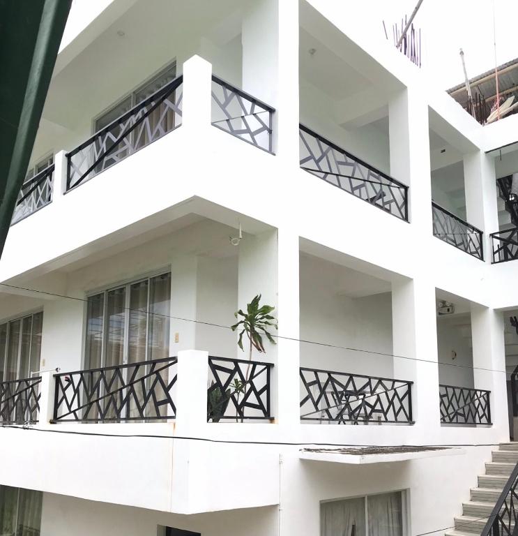 a white building with balconies and a plant on it at Vargas Apartelle in Boracay