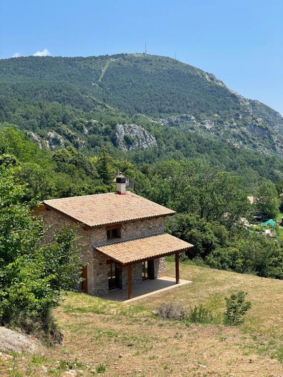 una pequeña casa de piedra con techo en una colina en Casa de les Escoles, Espinalbet - ALBERGA, en Castellar del Riu