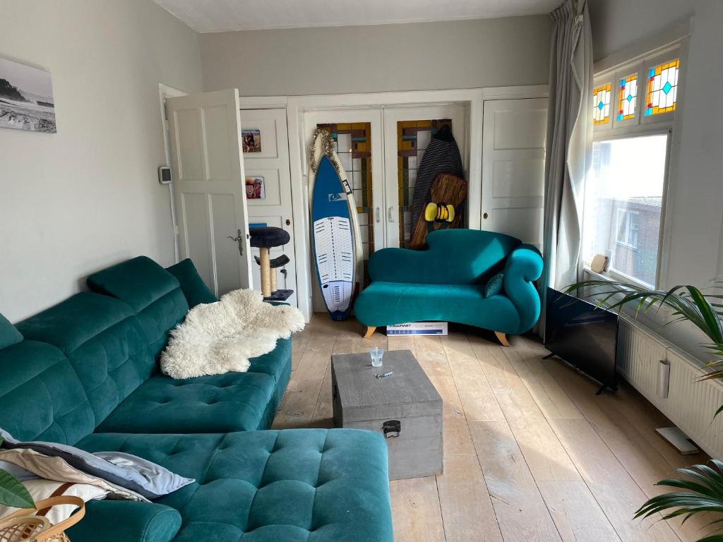 een woonkamer met een blauwe bank en surfplanken bij Nice apartment next to the beach in Scheveningen