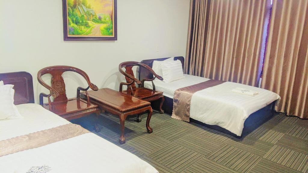 a hotel room with two beds and a chair at Khách sạn Hương Thầm Tây Ninh in Tây Ninh