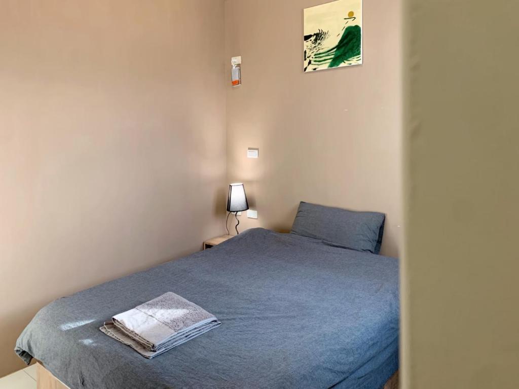金寧鄉的住宿－白貓民宿：慢活金門住這裡，一间卧室配有一张带蓝色床单和一盏灯的床。