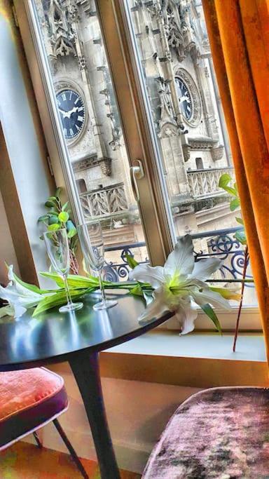 une table avec des fleurs devant une fenêtre dans l'établissement Suite st lô 1 Rouen (centre historique), à Rouen