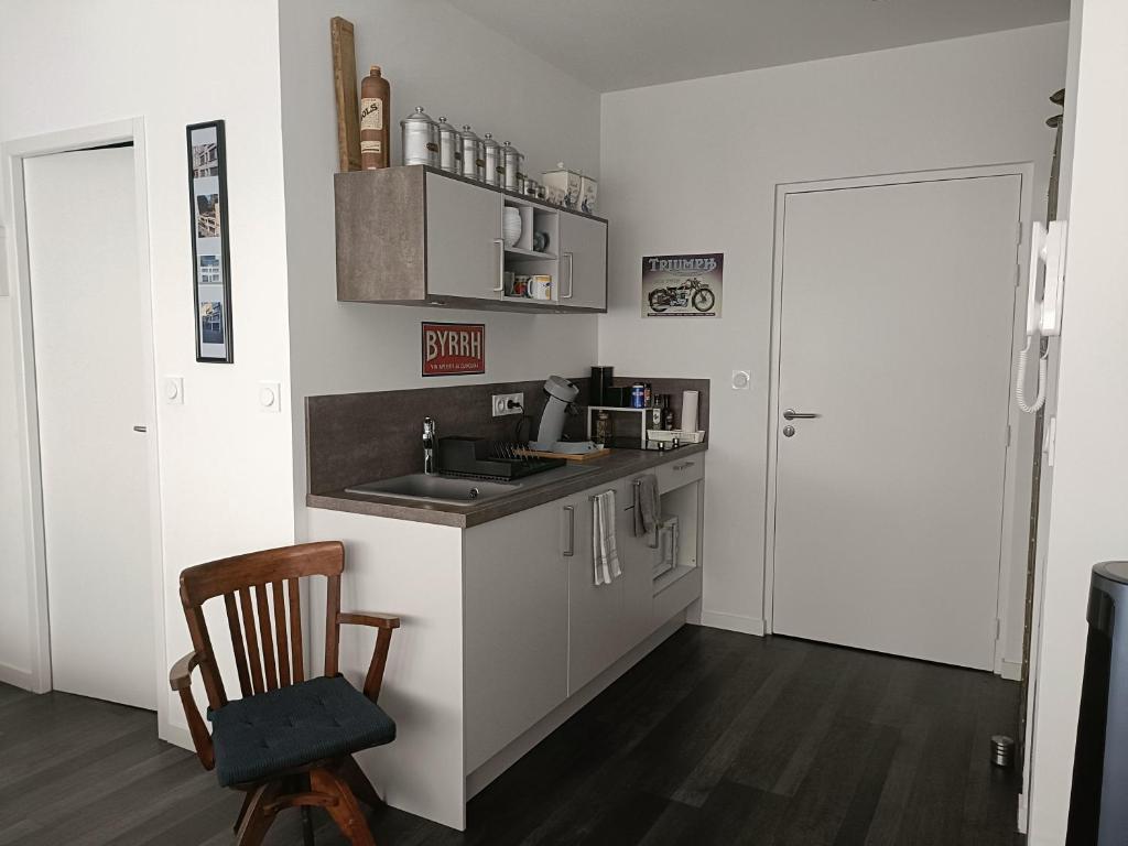 uma pequena cozinha com um lavatório e uma cadeira em L'imprimerie, charmant pied à terre, tout confort em Rennes