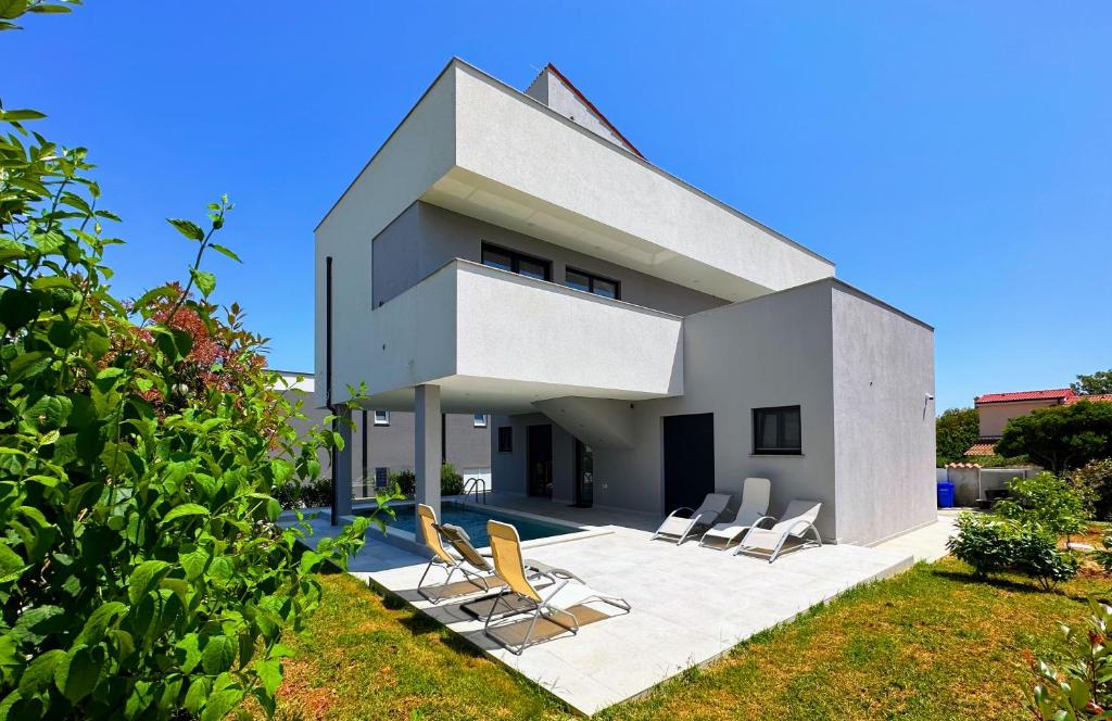 une maison avec des chaises assises sur une terrasse dans l'établissement Favoloso Duplex Volme - Banjole, Pula, Croazia, à Banjole