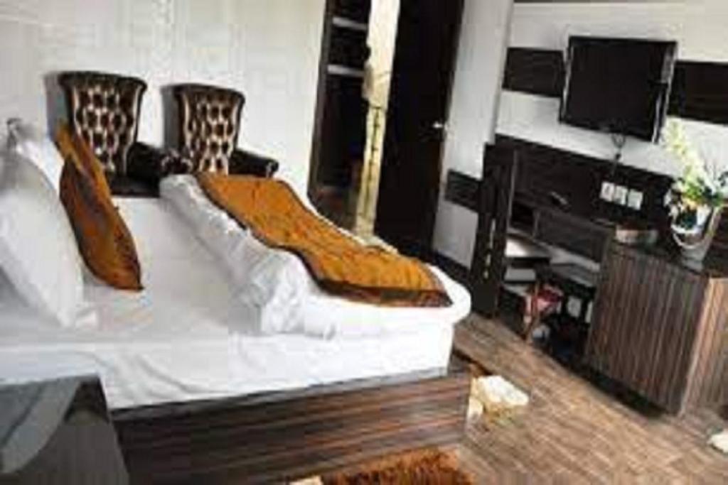 a living room with a bed and a flat screen tv at Hotel Riya Palace By Standards in Haldwāni